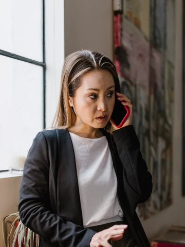 Female manager in a black blazer on a phone call by the office window