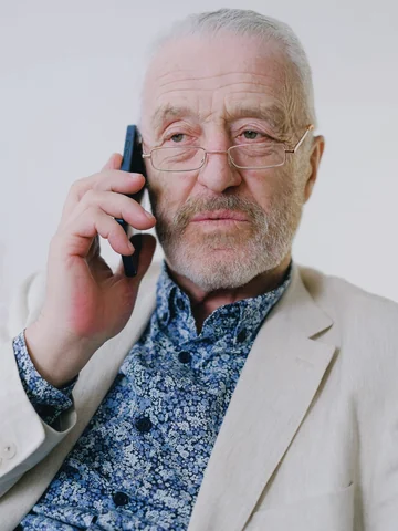 Senior businessman with glasses in a beige blazer on a phone call