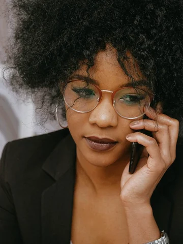 Businesswoman with glasses in a black blazer talking on the phone